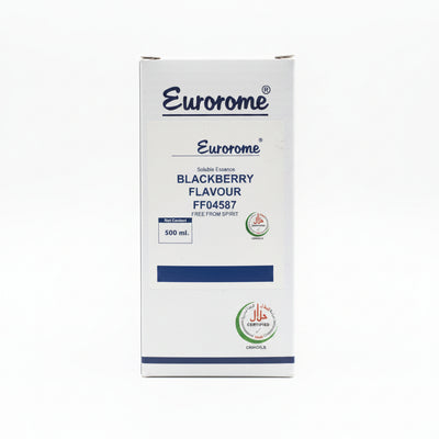 A hand holding a box of Eurorome Blackberry Flavour soluble essence, showing the front label and product details, with other boxes and containers visible in the background.