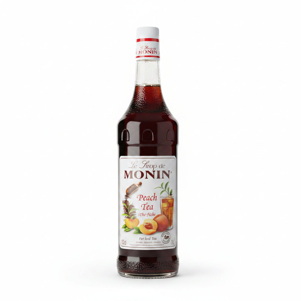 Bottle of Monin Peach Tea syrup in front of stacked cardboard boxes.