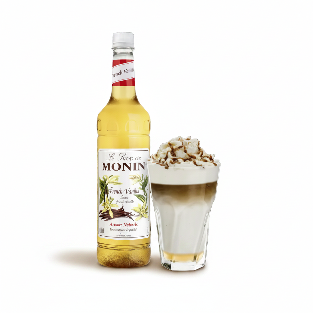 A bottle of Le Froid de Monin French Vanilla syrup stands next to a layered latte topped with whipped cream and chocolate shavings on a white background.