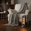Portable space heater next to a cozy armchair with a blanket in a living room setting.