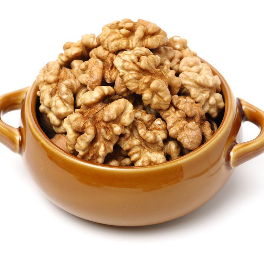 Ceramic bowl filled with walnuts on a white background