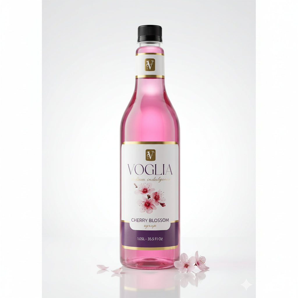A bottle of Voglia Cherry Blossom syrup with pink liquid, a white and purple label with cherry blossom illustrations, and a black cap, set against a clean white background with decorative cherry blossom petals at the base.