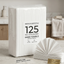 A package of 125 premium hand towels sits on a light stone countertop in a softly blurred kitchen setting, with an open stack of white hand towels displayed beside it and a small gold badge reading Premium Pack.