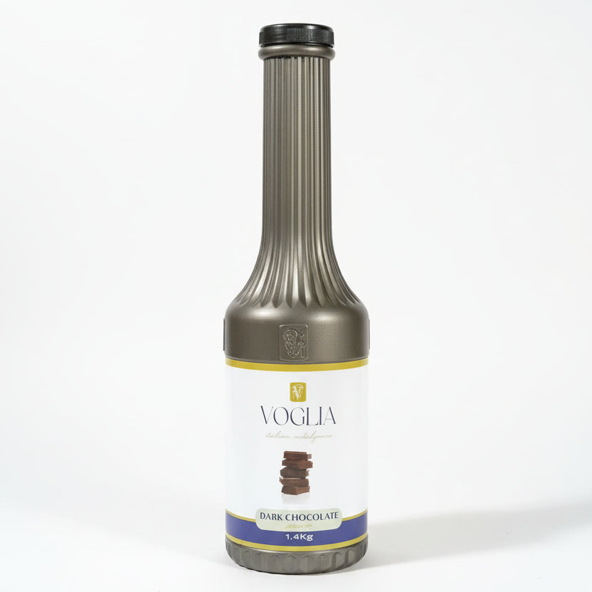 Bottle of Vogel's dark chocolate syrup on a background of stacked cardboard boxes.